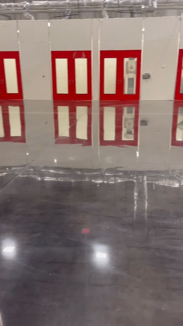 Reflective industrial concrete floor in front of red doors